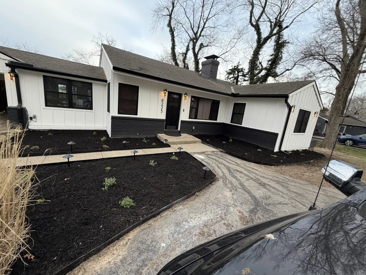 Modern farmhouse front yard with fresh black mulch beds and landscape lighting stakes — Gladstone MO