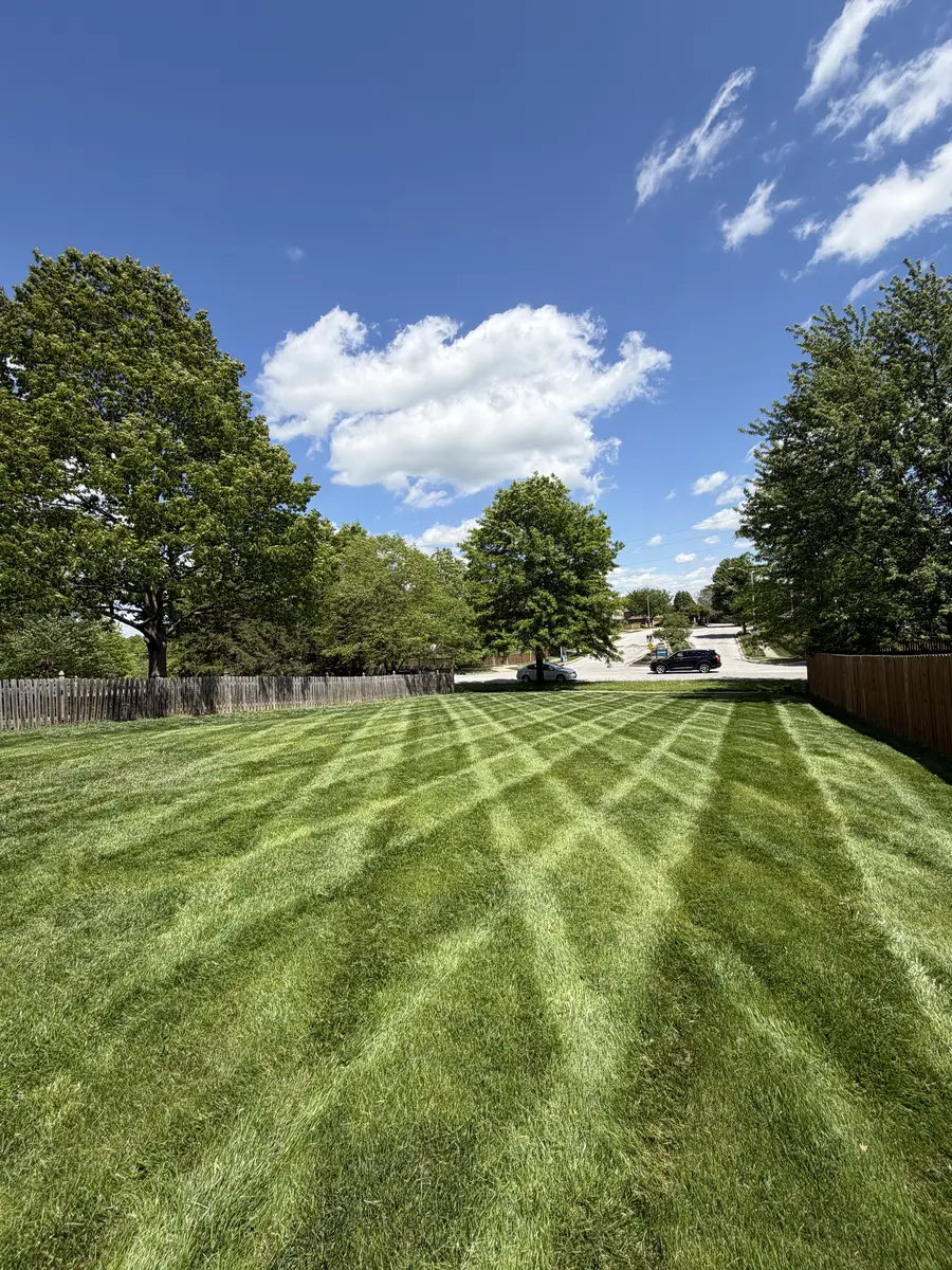Precision diamond-pattern mowing stripes across large open residential lawn — Liberty MO