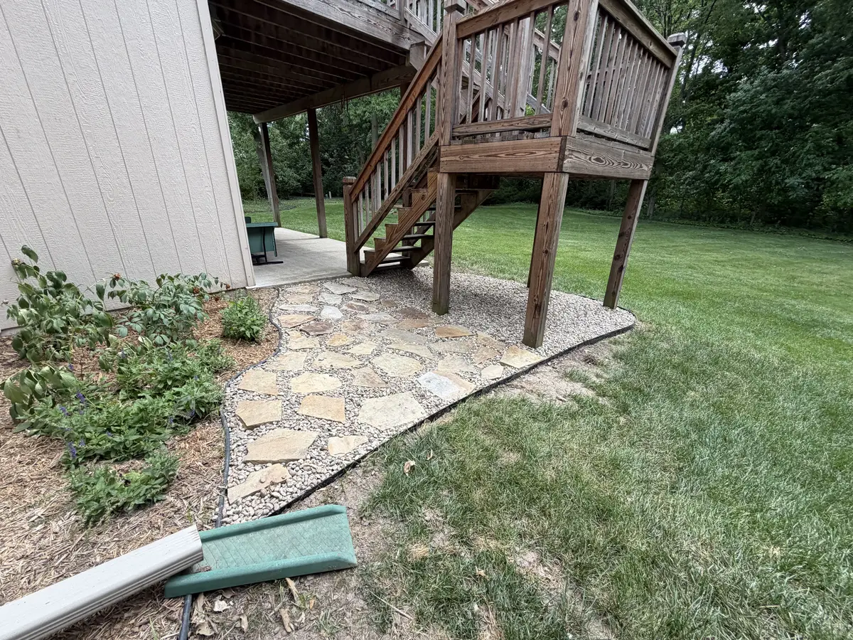 Natural flagstone patio with gravel base installed under raised wood deck — Smithville MO