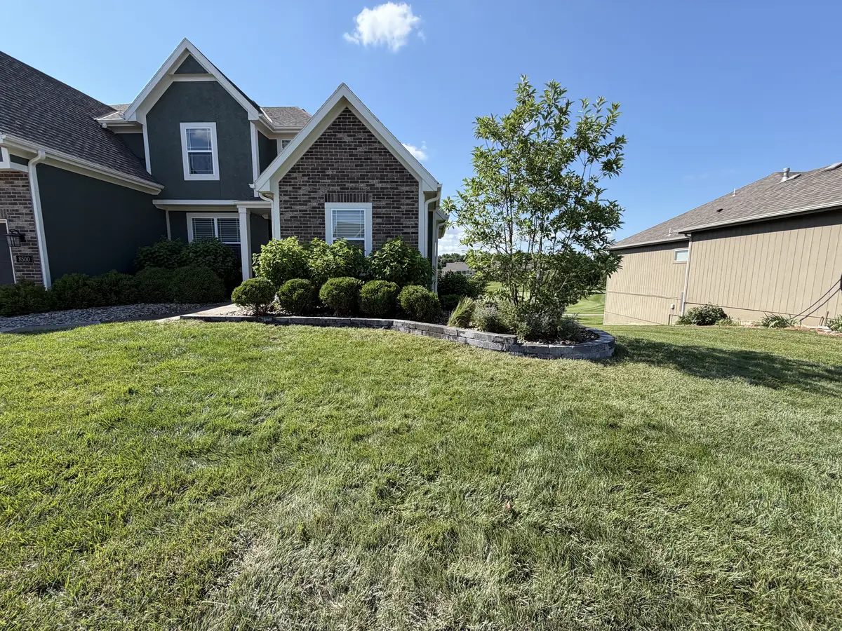 Front yard stone landscape border with trimmed globe shrubs and ornamental tree — Smithville MO