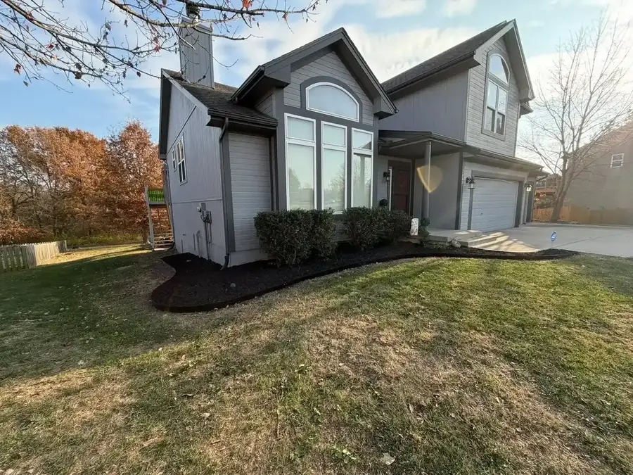 Fresh black mulch installation around foundation shrubs on gray two-story home — landscaping in Smithville MO