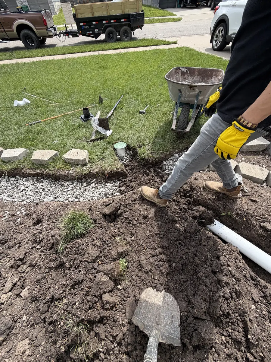 Crew installing landscape edging and drainage pipe with stone border — Smithville MO