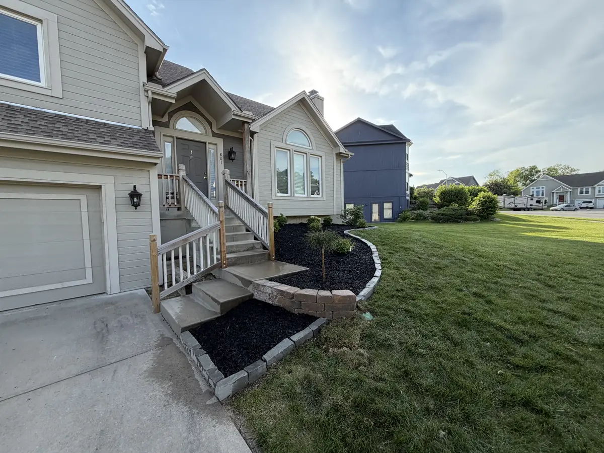 Curved stone retaining wall framing front entry planting bed with fresh mulch — Liberty MO